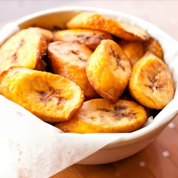 A white bowl filled with golden-brown, fried plantain slices, a Peruvian side dish from Don Pollo.