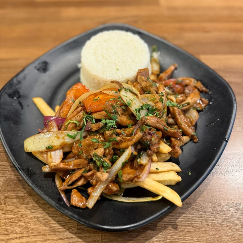 Don Pollo's Lomo Saltado, a Peruvian stir-fry with beef, onions, tomatoes, fries, and rice.