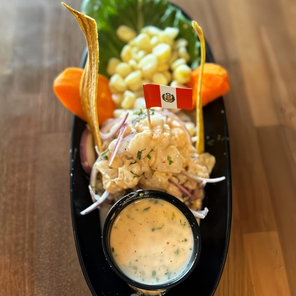 Peruvian ceviche with corn, plantain chips, and a Peruvian flag, served with a side of sauce.